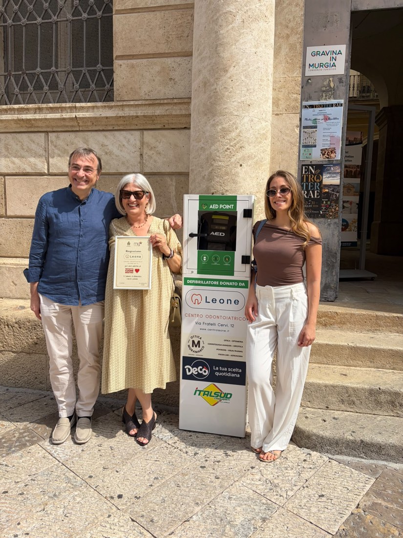 Il Dr. Mario Leone, la Dr.ssa Maria Ardito con la targa di ringraziamento del progetto Cuore Nostro e la Dr.ssa Giulia Leone accanto alla colonnina DAE donata dal Centro Odontoiatrico Leone in Piazza Cattedrale a Gravina in Puglia